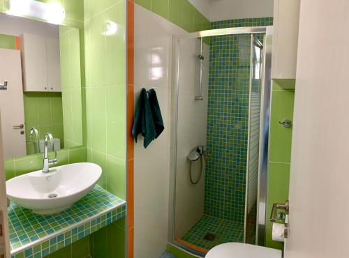 a green bathroom with a sink and a shower at BIO Garden New House in Gonia