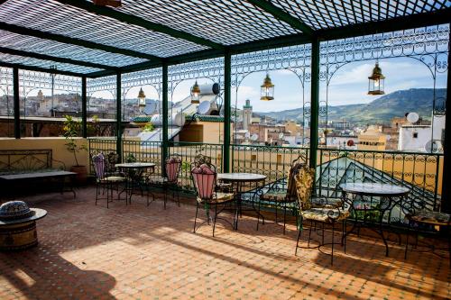 eine Terrasse mit Tischen und Stühlen auf dem Balkon in der Unterkunft Ryad Zahrat Fes in Fès