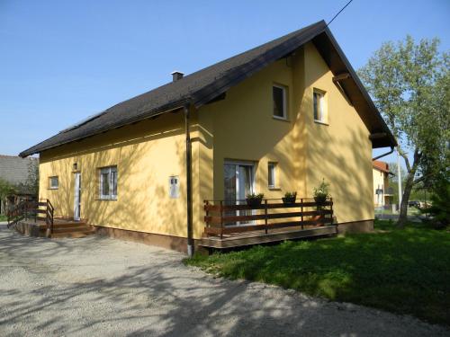 a yellow house with a porch and a yard at Apartmani Slavek in Jastrebarsko