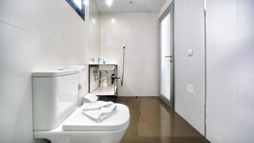 a white bathroom with a toilet and a sink at Ura Nido del Águila in Puerto Rico de Gran Canaria