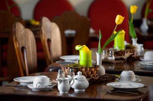 a table with plates and cups and yellow flowers on it at Land-gut-Hotel BurgBlick in Bad Kreuznach