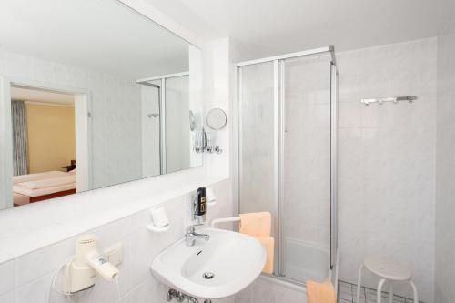 a white bathroom with a sink and a shower at Land-gut-Hotel BurgBlick in Bad Kreuznach