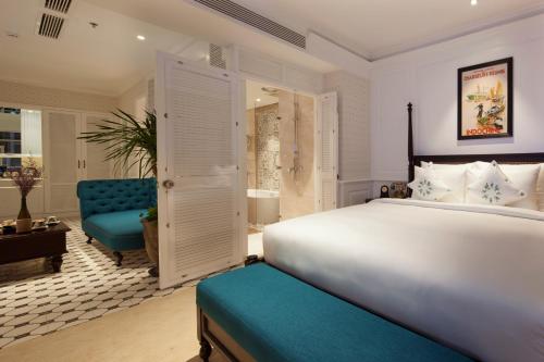 a bedroom with a large bed and a blue chair at Alagon D'antique Hotel & Spa in Ho Chi Minh City