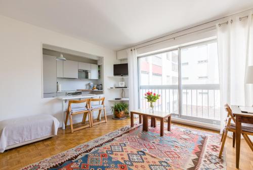 un salon avec une table et une grande fenêtre dans l'établissement Veeve - A Pop of Colour, à Paris
