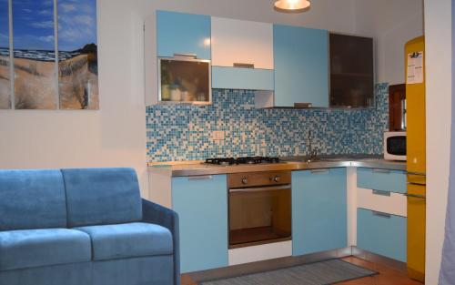 cocina con armarios blancos y sofá azul en IL MARE DI OLBIA Holiday Apartment, en Olbia