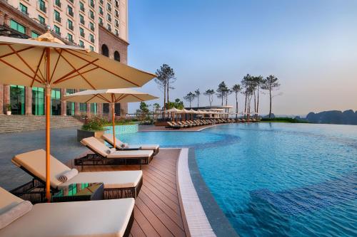 uma piscina num hotel com cadeiras e guarda-sóis em FLC Halong Bay Golf Club & Luxury Resort em Ha Long