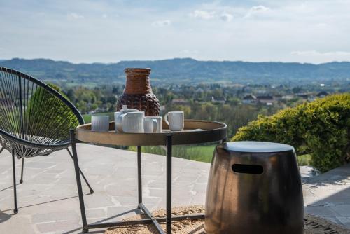 a table with cups and a vase and a chair at CHAMBRE AVEC VUE in Domessin