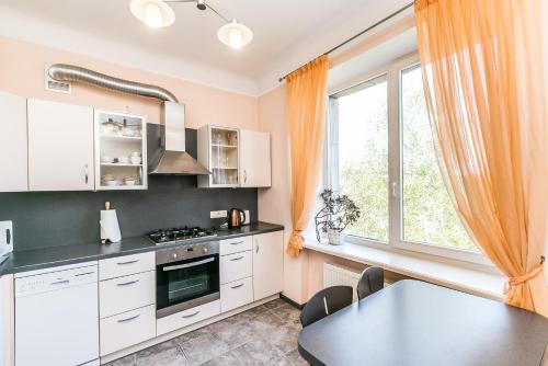 cocina con armarios blancos, mesa y ventana en Eksporta Street Apartment en Riga