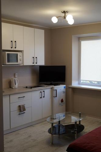 a kitchen with white cabinets and a table and a window at Anyksciu liuksas in Anykščiai