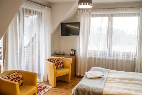 a bedroom with a bed and two chairs and a tv at Willa Ryś in Zakopane