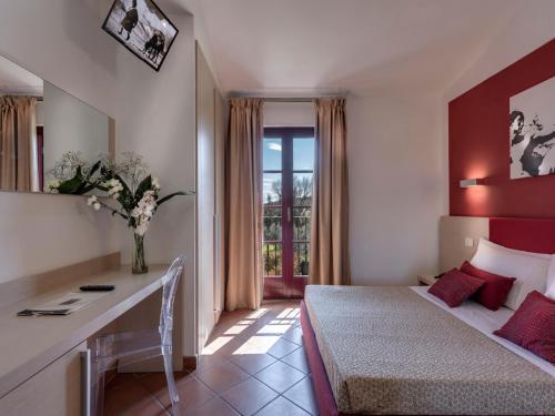 a hotel room with a bed and a desk in it at Hotel & Restaurant Casolare Le Terre Rosse in San Gimignano