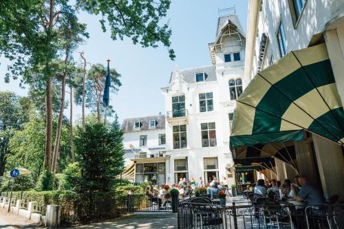 a group of people sitting at tables in front of a building at Parkhotel Mastbosch Breda in Breda