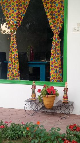 a window with curtains and a pot of flowers on a table at Coral Country Homestay in Agra