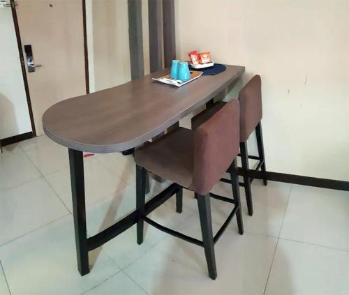 a wooden table with two chairs and a table with a box on it at Junikastay BLagoon Melaka in Melaka