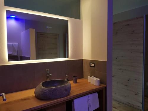 La salle de bains est pourvue d'un lavabo en pierre et d'un miroir. dans l'établissement Aparthotel Malga, à Caldaro