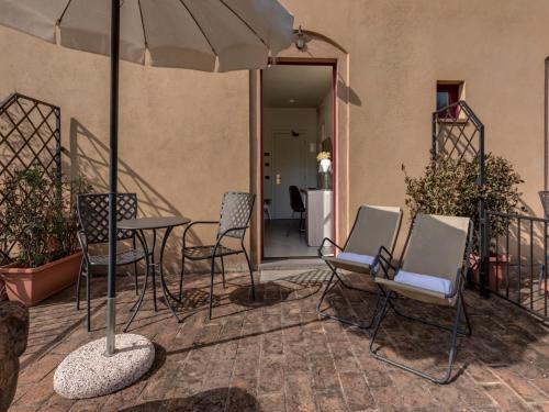 a patio with chairs and a table and an umbrella at Hotel & Restaurant Casolare Le Terre Rosse in San Gimignano