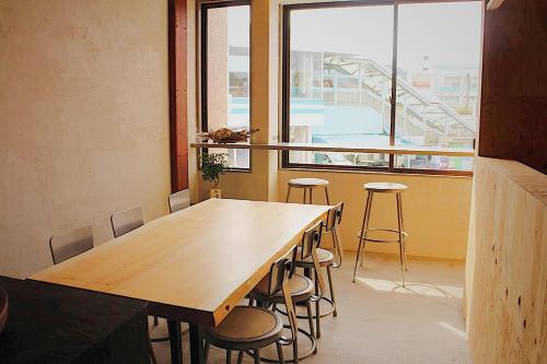 a table and chairs in a room with a large window at WhyKumano in Nachikatsuura