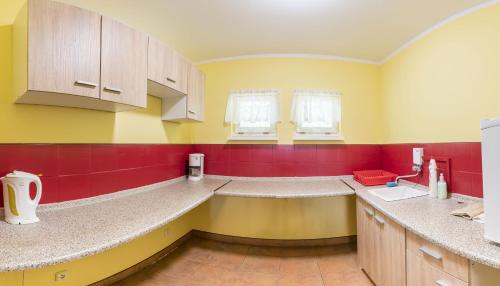 a kitchen with yellow and red walls and counters at Szałas Muflon - Mufflonhütte in Jelenia Góra