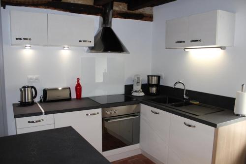 eine Küche mit weißen Schränken und einer schwarzen Arbeitsplatte in der Unterkunft Gite des Celliers in Alise-Sainte-Reine