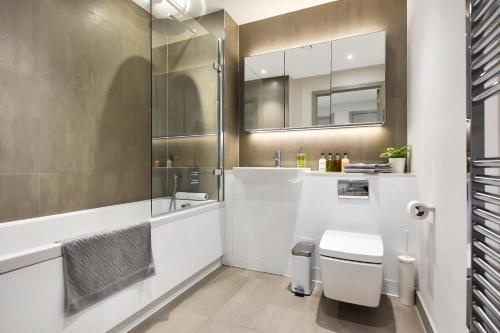 bagno con servizi igienici, lavandino e specchio di Esquire Apartments Ealing a Londra