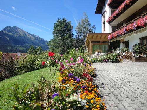 - un jardin avec des fleurs colorées à côté d'un bâtiment dans l'établissement Apartment Austria, à Tannheim