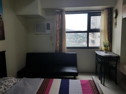 a bedroom with a bed and a window and a chair at Horizon 101 Cebu by KC Condo in Cebu City