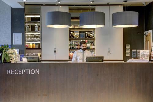 a man standing behind a counter in a restaurant at Best Western Chiswick Palace & Suites London in London