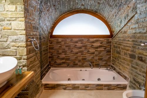 a bath tub in a bathroom with an arched window at Hotel Restaurant Emblema in Petrelë
