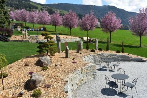 een tuin met tafels en stoelen en roze bomen bij Hotel Nussbaumerhof *** in Rodengo