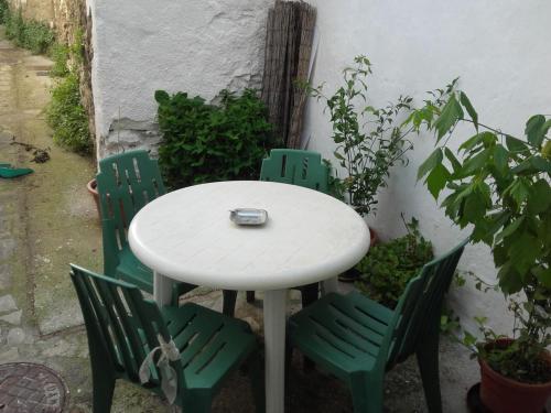 una mesa blanca y cuatro sillas verdes en un patio en Júbrique en Jubrique