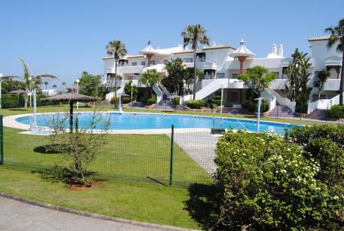 a swimming pool in front of a apartment complex at Novo Sancti Petri Atardecer Planta baja in Chiclana de la Frontera