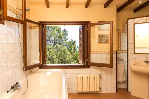 a bathroom with a tub and a sink and a window at Sa Rondalla - Formentera in Playa Migjorn