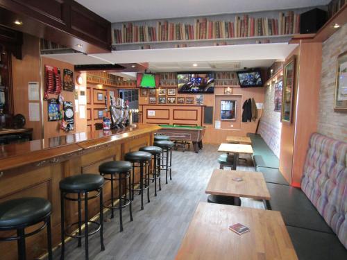 a bar with wooden stools and tables in a restaurant at The Red Lion Tavern in Fochabers