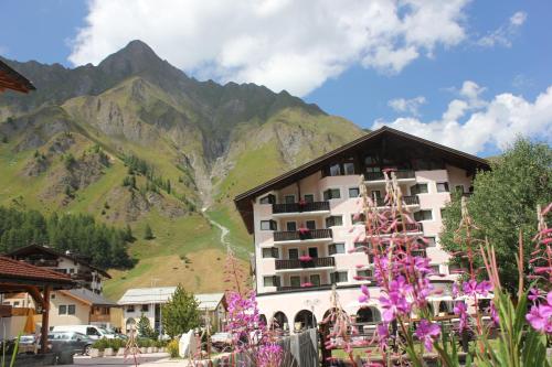 a hotel in front of a mountain with purple flowers at Chalet Silvretta Hotel & Spa in Samnaun