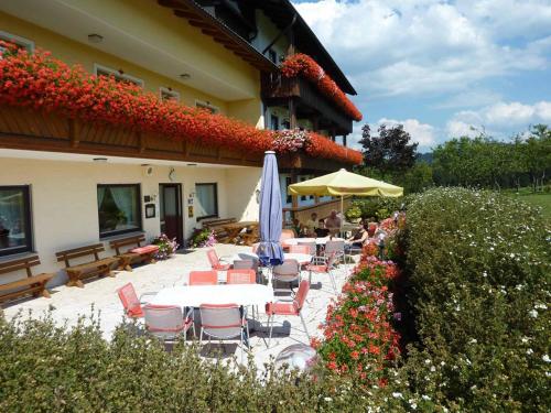 a patio with tables and umbrellas in front of a building at Hotel Märchenwald in Haidmühle