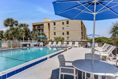 a pool with chairs and a table with an umbrella at Beachside Motel - Amelia Island in Amelia Island