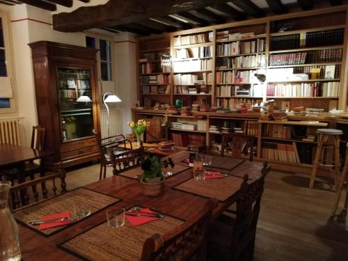 een eetkamer met een tafel en een aantal boeken bij La Virgule de Tanlay in Tanlay