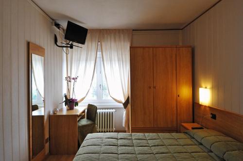 フォルガリーアにあるHotel Milanoのベッドルーム1室(ベッド1台、キャビネット、窓付)