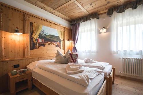 1 dormitorio con 1 cama en una habitación con paredes de madera en Chalet Alpenrose Bio Wellness Naturhotel, en Cogolo