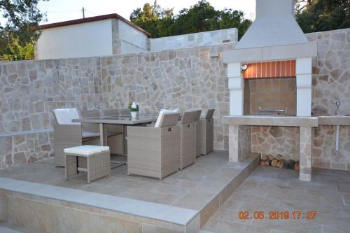 a patio with a table and chairs and a fireplace at Dreamlodge - Luxe Dalmatian Villa, private pool, parking, mooring, breathtaking sea & mountain view, at 150 m from idyllic private beach in Rogač