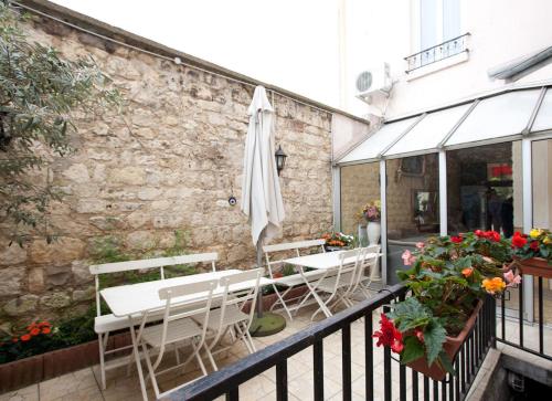 a patio with tables and an umbrella and flowers at Hôtel du Parc in Malakoff