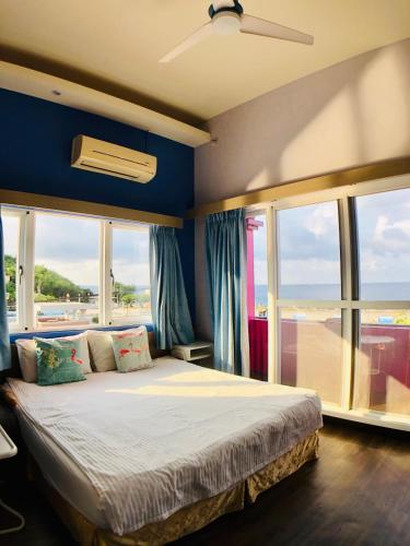 a bedroom with a bed with blue walls and windows at I WoW in Xiaoliuqiu