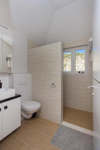 a bathroom with a toilet and a sink and a window at Villa Terra Rogoznica in Rogoznica
