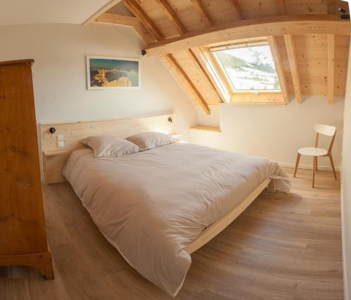 Schlafzimmer mit einem großen Bett und einem Fenster in der Unterkunft Gite de la Petite Ecole in Lans-en-Vercors
