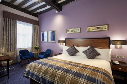 una camera d'albergo con letto, tavolo e sedie di The Bull a Gerrards Cross