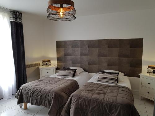 - une chambre avec 2 lits et un lustre dans l'établissement Hôtel L'ideal le Mountbatten, à Arromanches-les-Bains