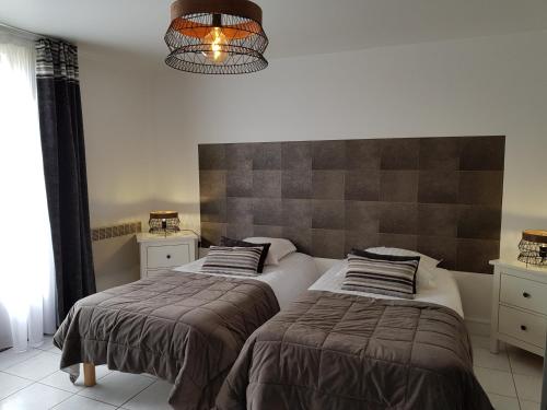 a bedroom with two beds and a chandelier at Hôtel L'ideal le Mountbatten in Arromanches-les-Bains