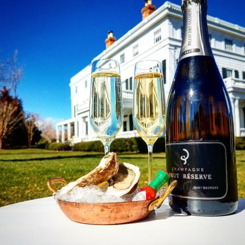 a bottle of wine and two glasses on a table at Topping Rose House in Bridgehampton