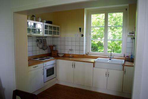 eine Küche mit weißen Schränken, einem Waschbecken und einem Fenster in der Unterkunft Alte Schule Osteroden in Merzen