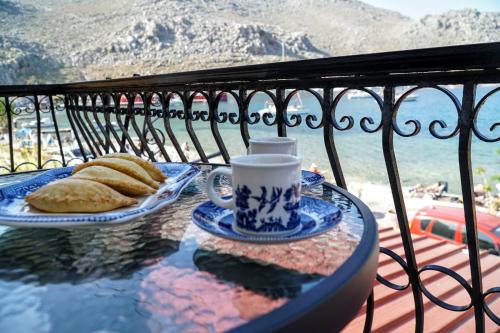 a table with a cup of coffee and bread on a balcony at Korali in Symi